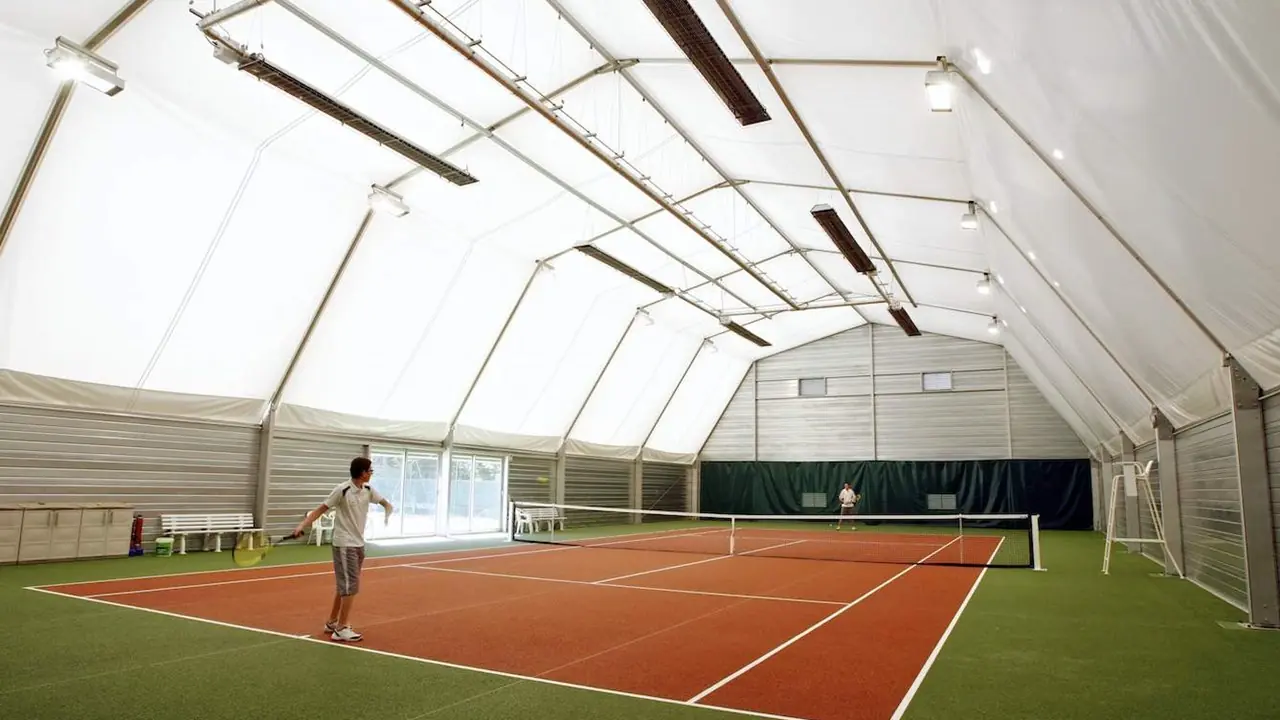 Spacious interior of 15x30m tennis tent with players in action, showcasing indoor court coverage and wind-resistant PVC fabric.