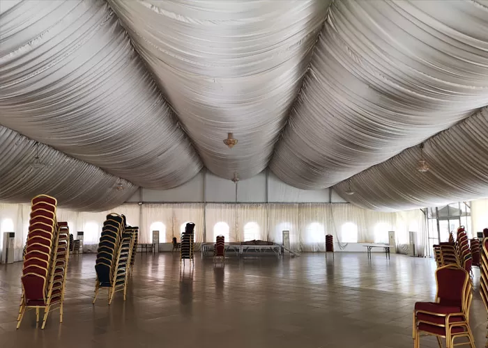Spacious interior of 25x30m church tent set up for a revival meeting with stage and rows of seating
