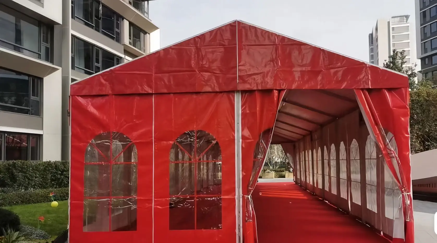 Exterior view of 24x6m red and white wedding tent set up in a garden with festive decorations